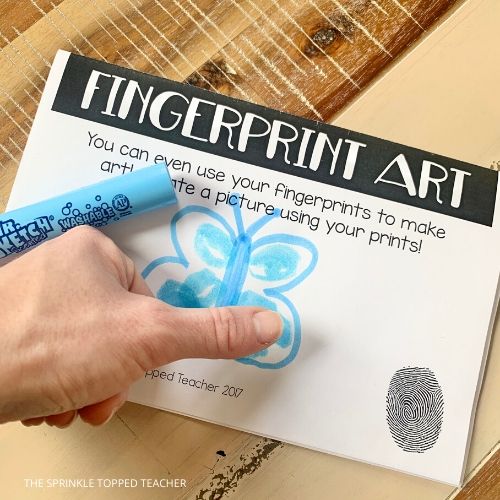 Student creating a butterfly in blue ink with fingerprints