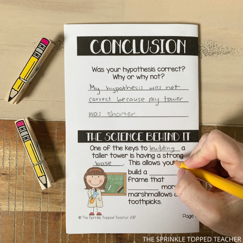 Student writing answers in their Marshmallow STEM activity notebook