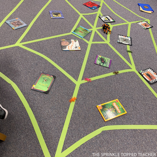 Spider web made of masking tape with little spiders and spider research books stuck in the web