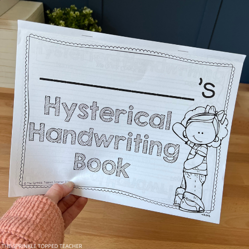 Teacher holding student's handwriting workbook as she preps for the next school year