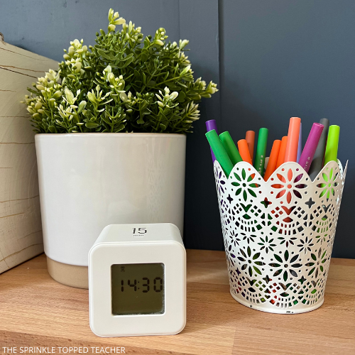 15 minute timer being used to help teacher prep for next school year, white basket of flair pens and plant sitting on wooden teacher desk