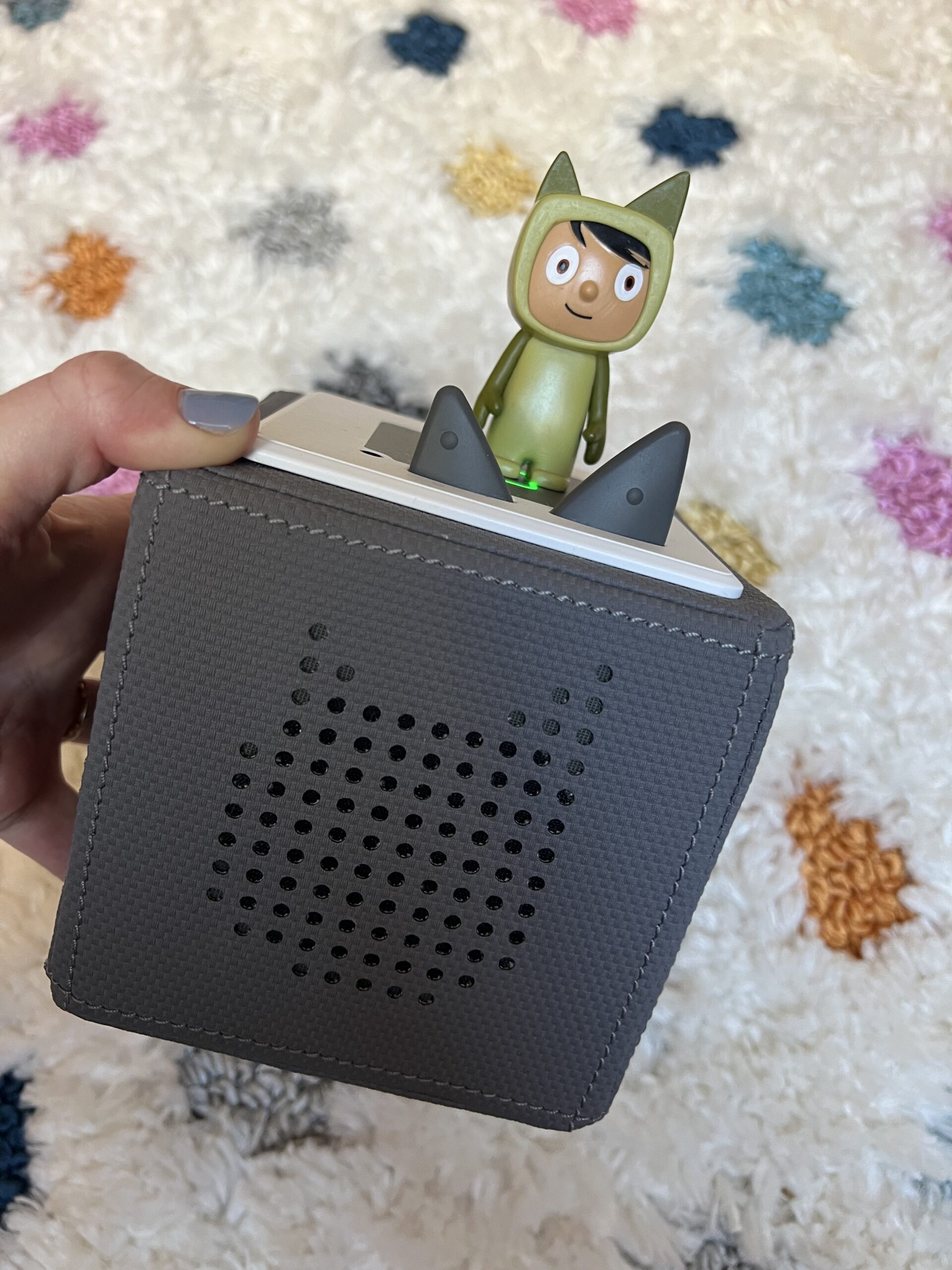 hand holding a gray tonies box with green tonie